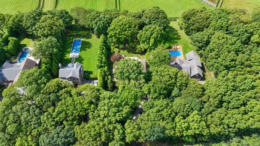 Vista aérea de terrenos arbolados con varios edificios y piscinas al aire libre.
