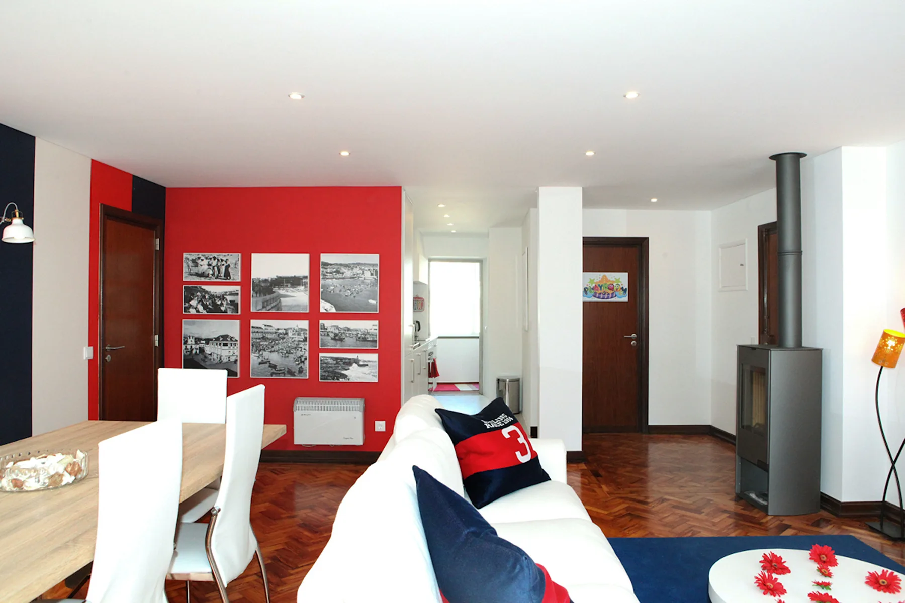 Sala de estar con pared roja, sofá y zona de comedor.