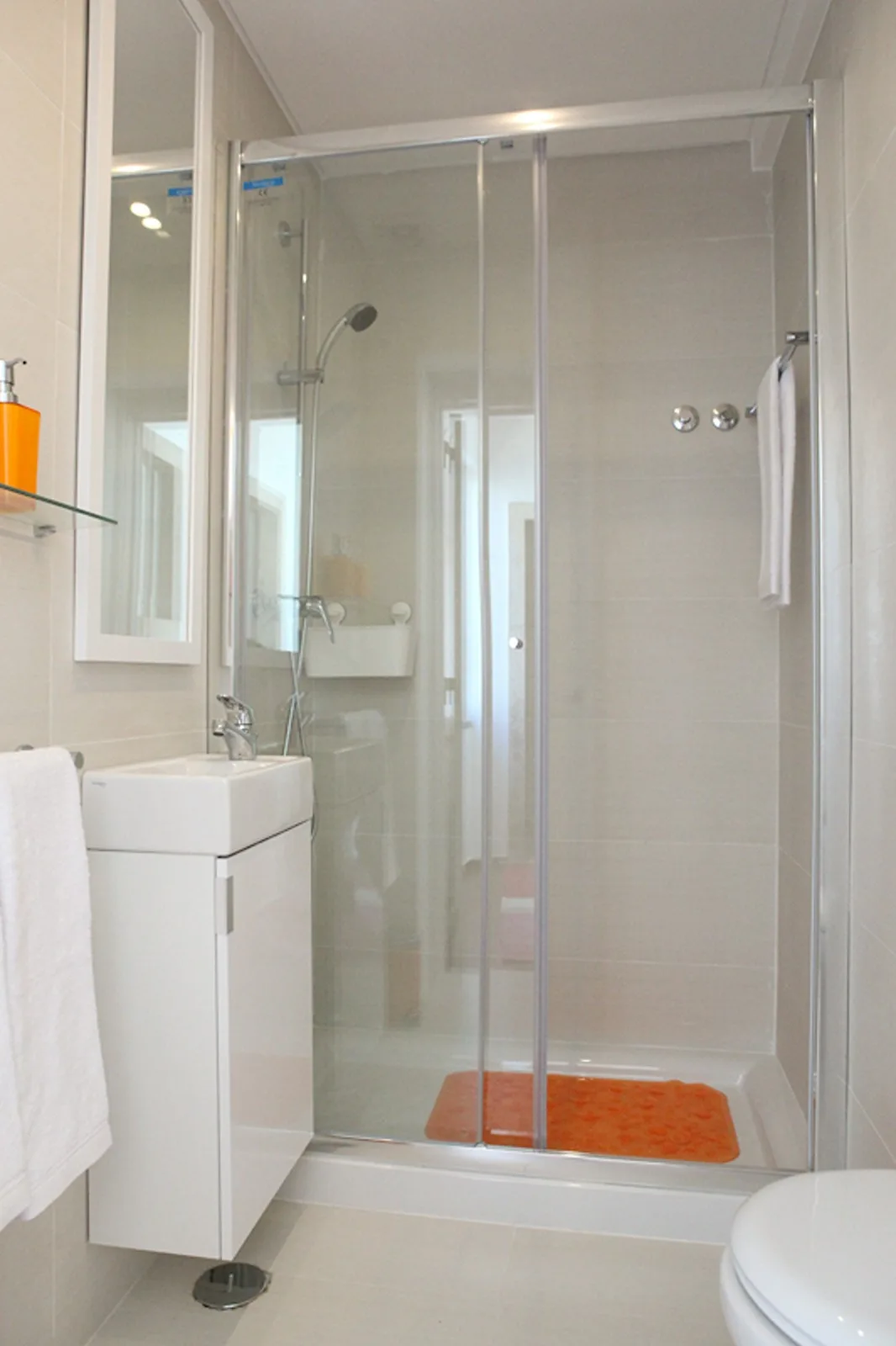 A bathroom with a glass-enclosed shower and a white sink cabinet.
