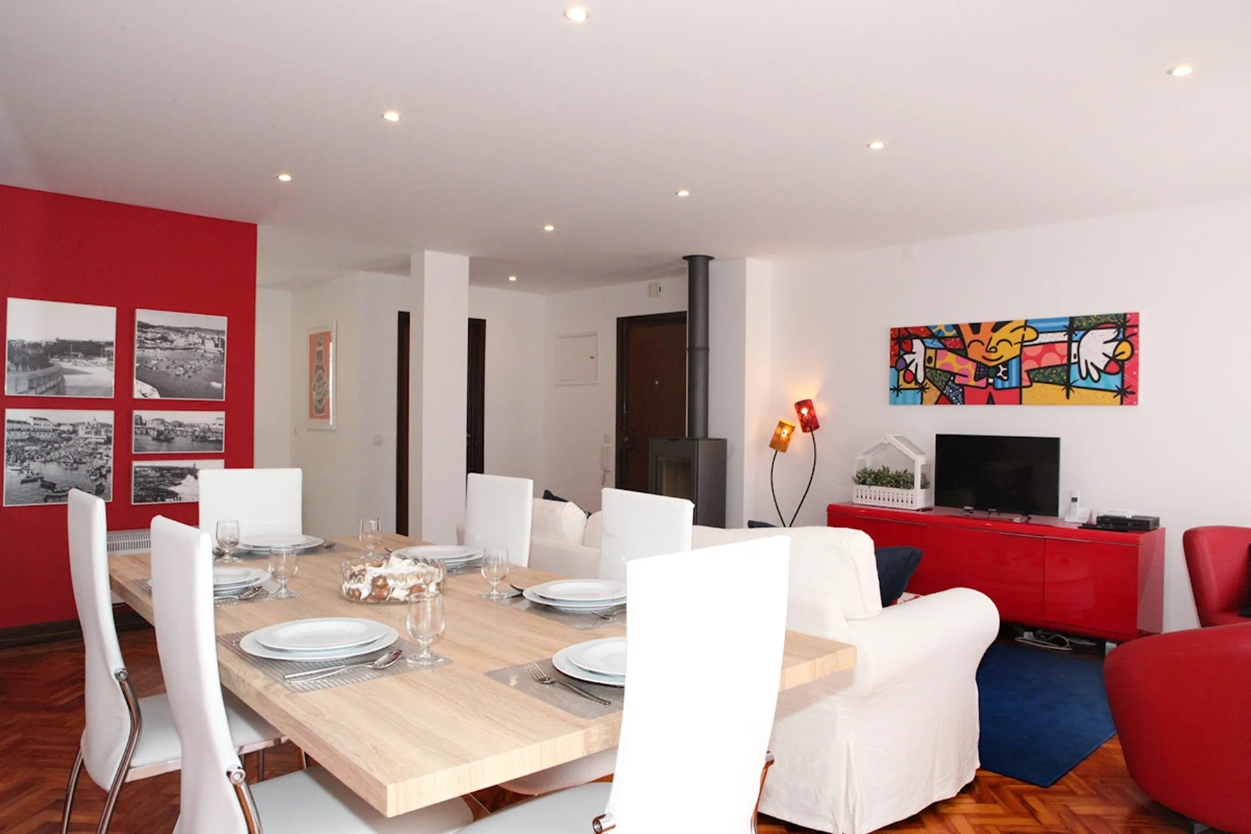 Zona de comedor y sala de estar con una mesa puesta, asientos y un televisor.