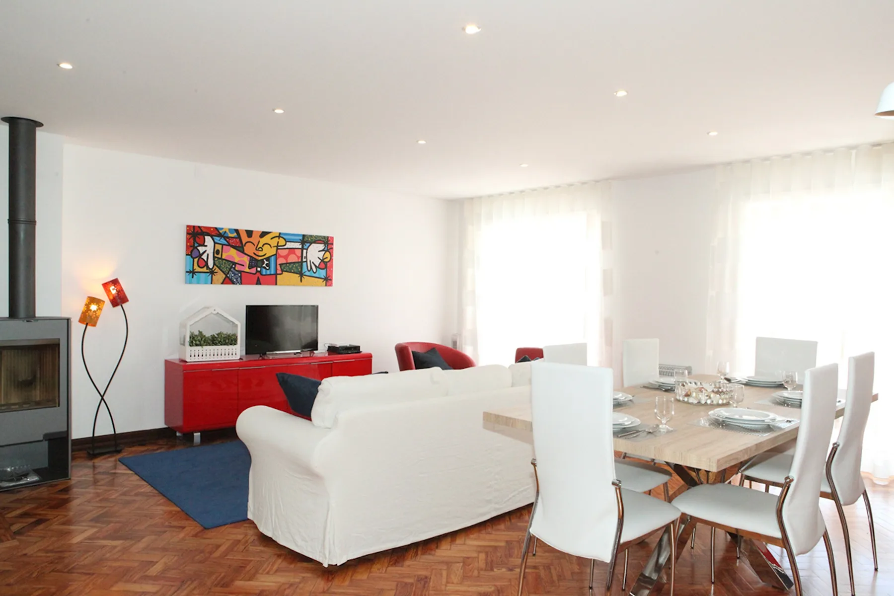 Una luminosa sala de estar y comedor con asientos blancos y una mesa puesta.