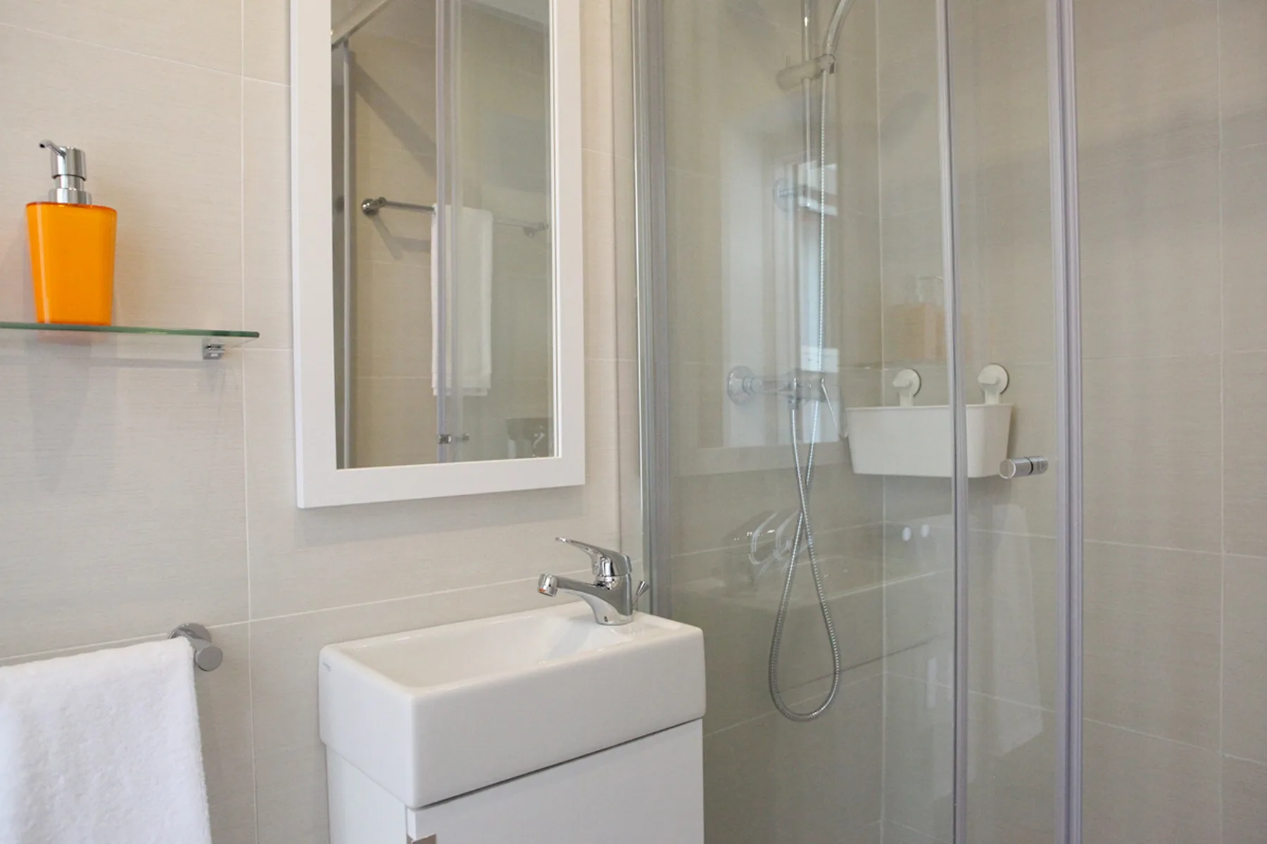 A bright bathroom with a sink, mirror, and glass shower.