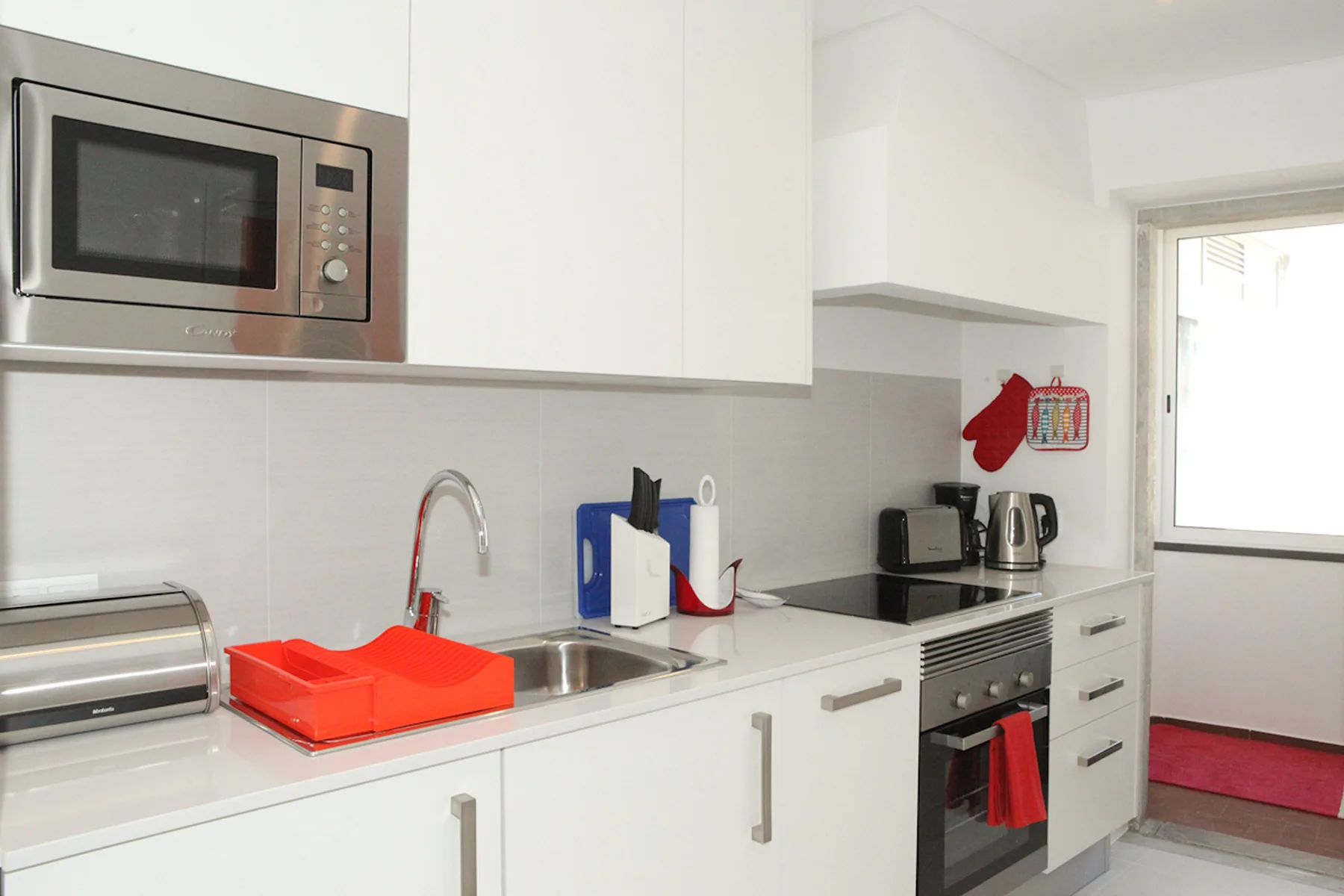 A modern kitchen with white cabinets, a sink, and built-in appliances.