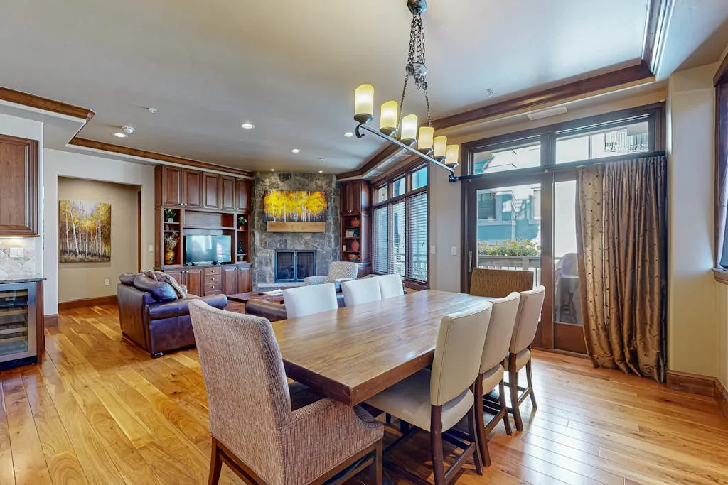 A dining area with a long wooden table and seating beside a living room.