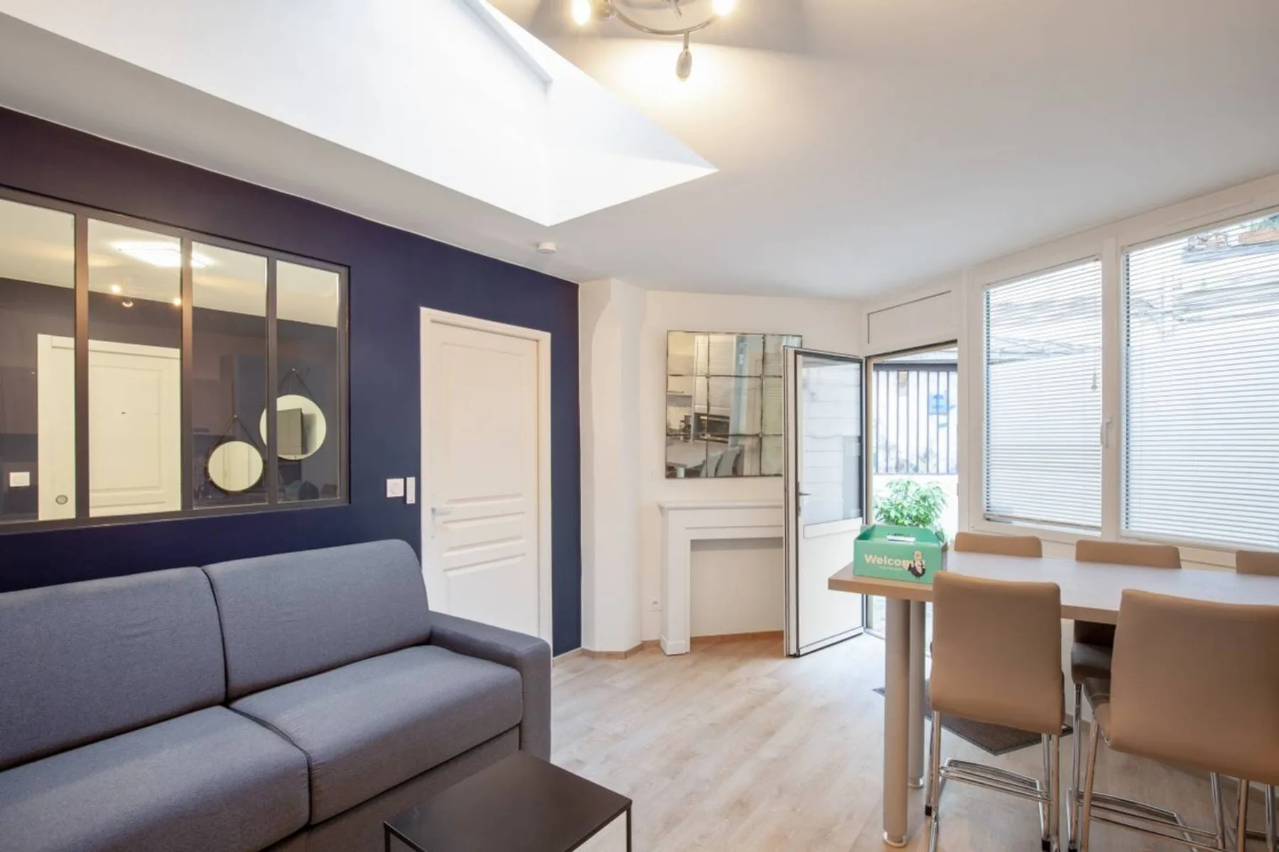 A bright living area with seating beside a dining table and large windows.
