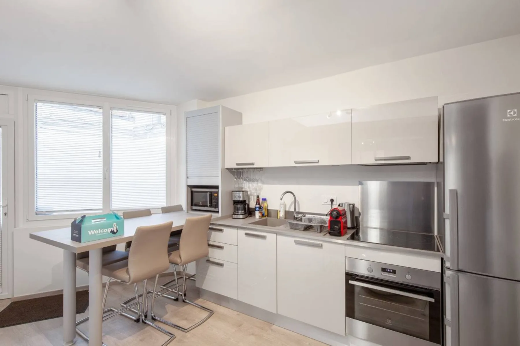 A bright kitchen with white cabinets, stainless steel appliances, and a dining table.