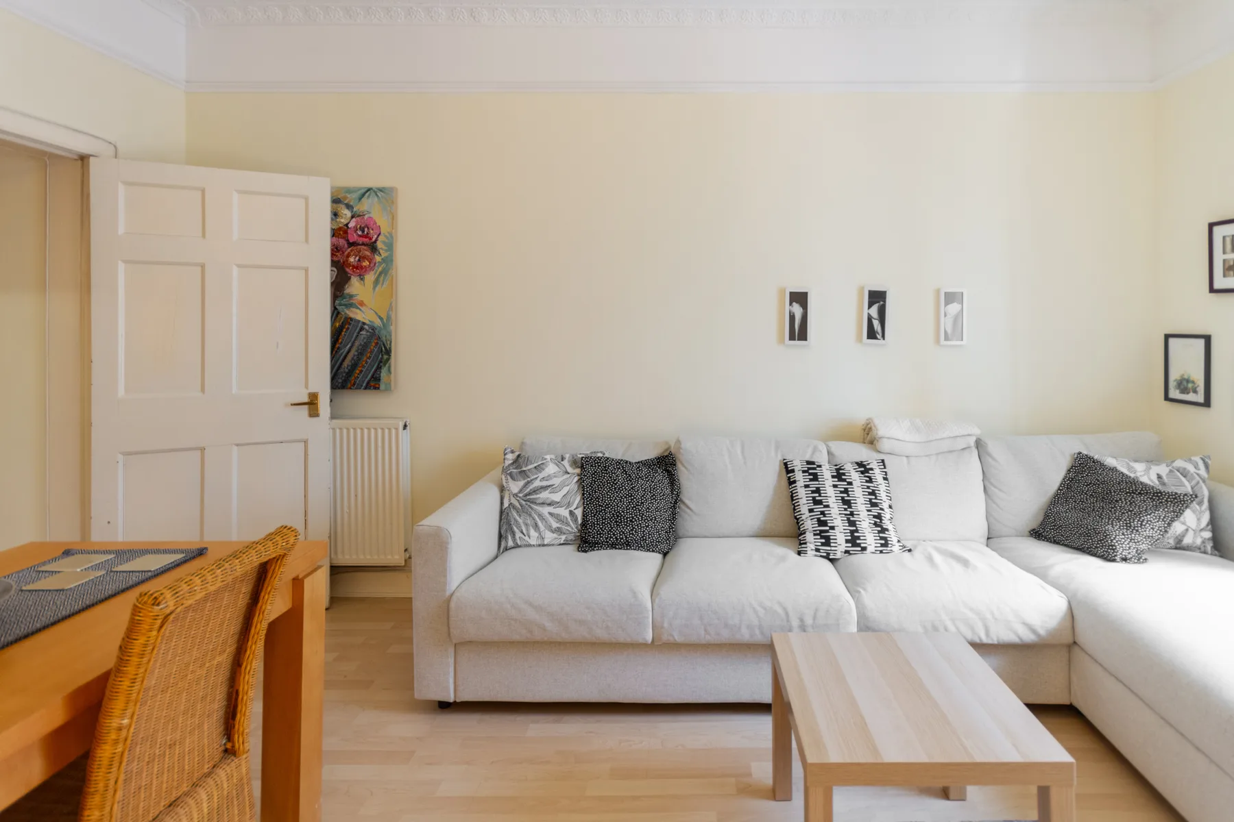 A bright living room with a white sectional and a light wood coffee table.