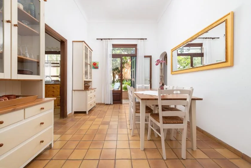 A bright dining room with a wooden table and a large wall mirror.