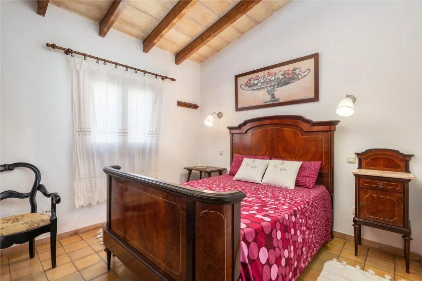 A bedroom with a wooden bed, patterned bedding, and a curtained window.