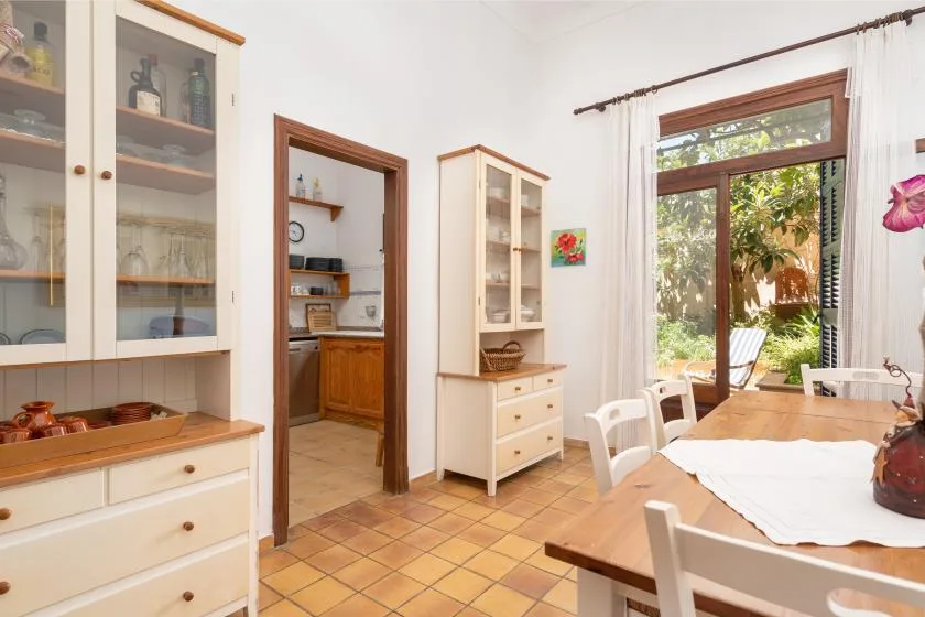 A bright dining area with a wooden table beside a large window overlooking greenery.