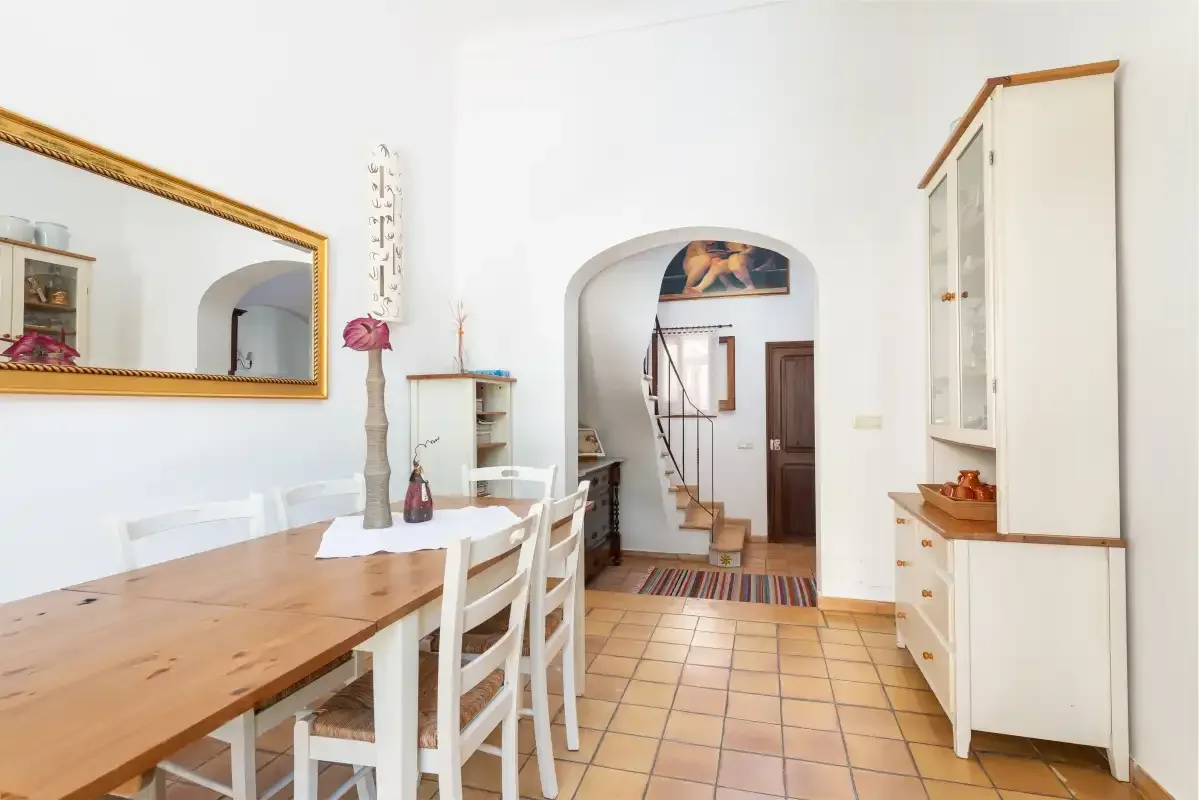A dining area with a wooden table opens into a hallway.