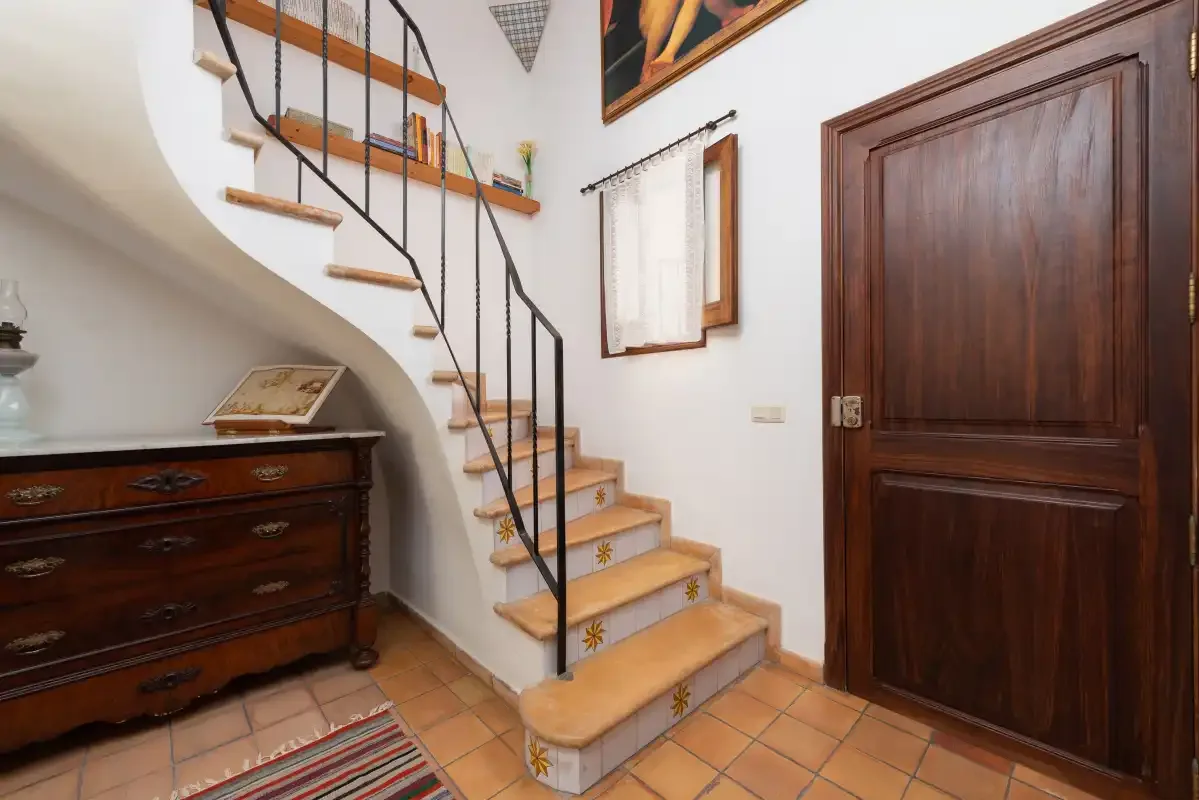 An interior entryway with a staircase, wooden chest, and dark wooden door.