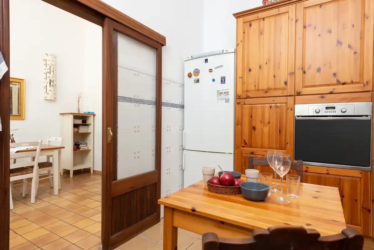 A kitchen and dining area with wooden cabinetry and a table set with dishes.