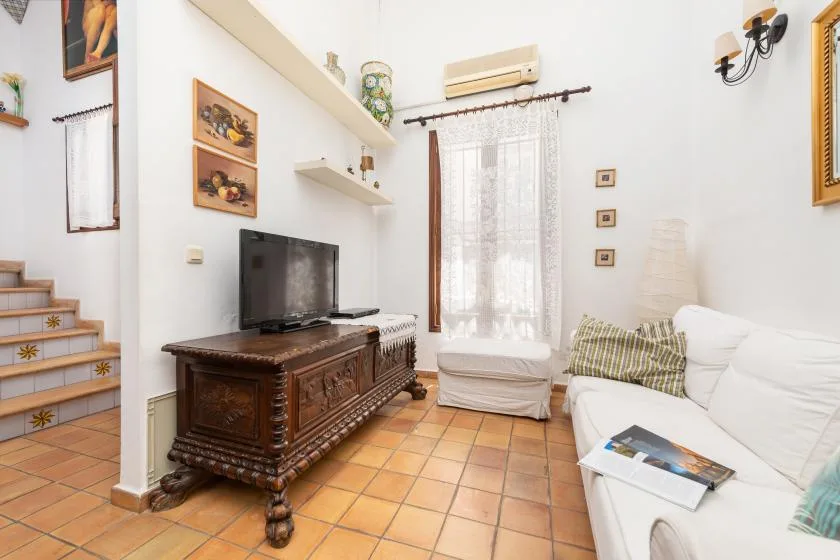 A living room with a television, seating, and a tiled floor.