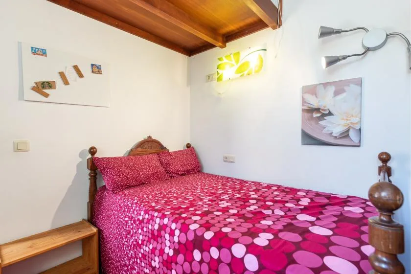 A bedroom with a bed covered in bright pink patterned bedding.
