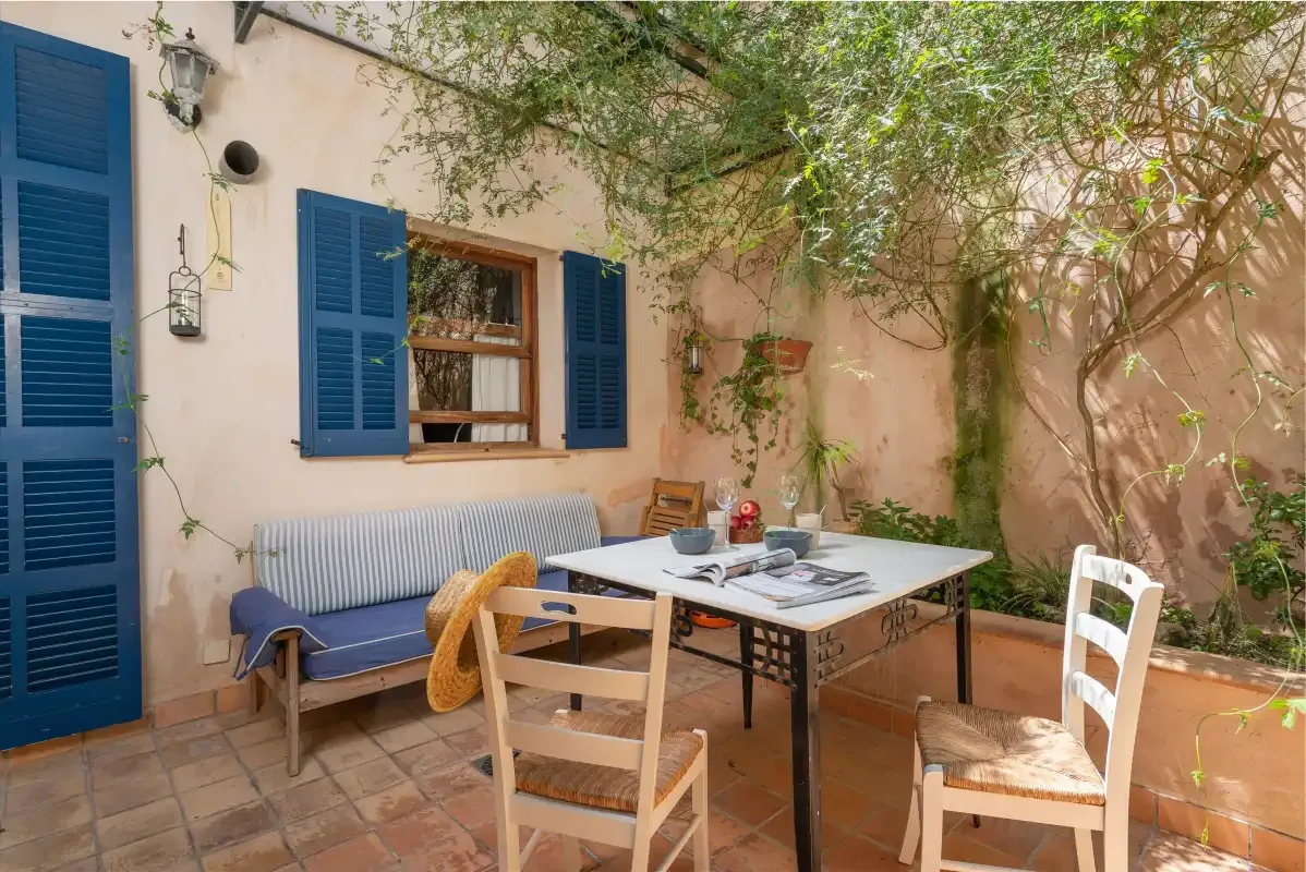 A courtyard dining area with a table and chairs beside a peach-colored wall.