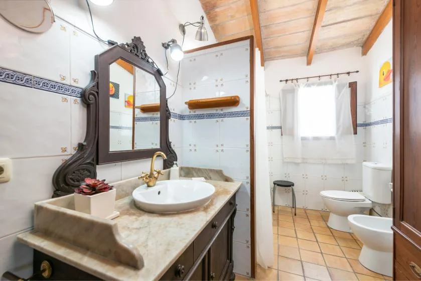 A tiled bathroom with a vanity, mirror, shower area, and toilet.