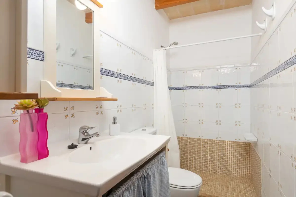 A tiled bathroom with a sink, mirror, and shower.