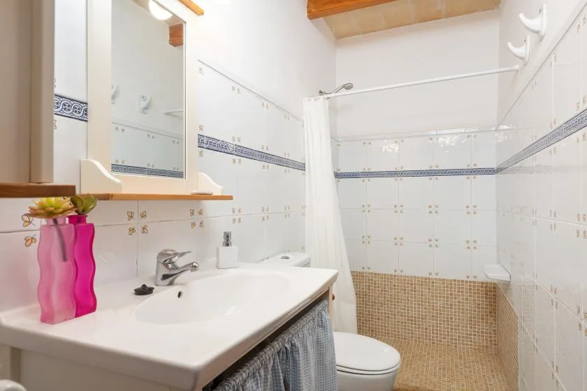 A tiled bathroom with a sink, mirror, and shower curtain.