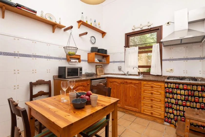 A kitchen with wooden cabinets, a dining table, and a window above the sink.