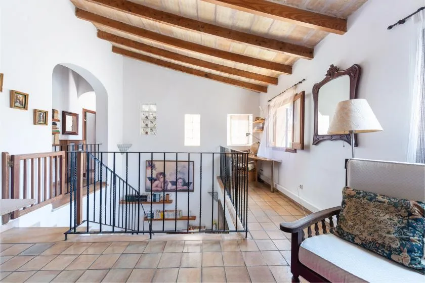 A bright interior landing with tiled flooring and a black metal railing.