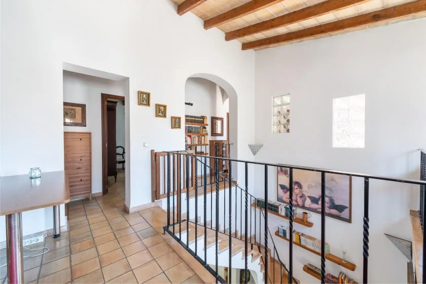 An interior landing overlooks a stairwell, with bookshelves and framed pictures nearby.