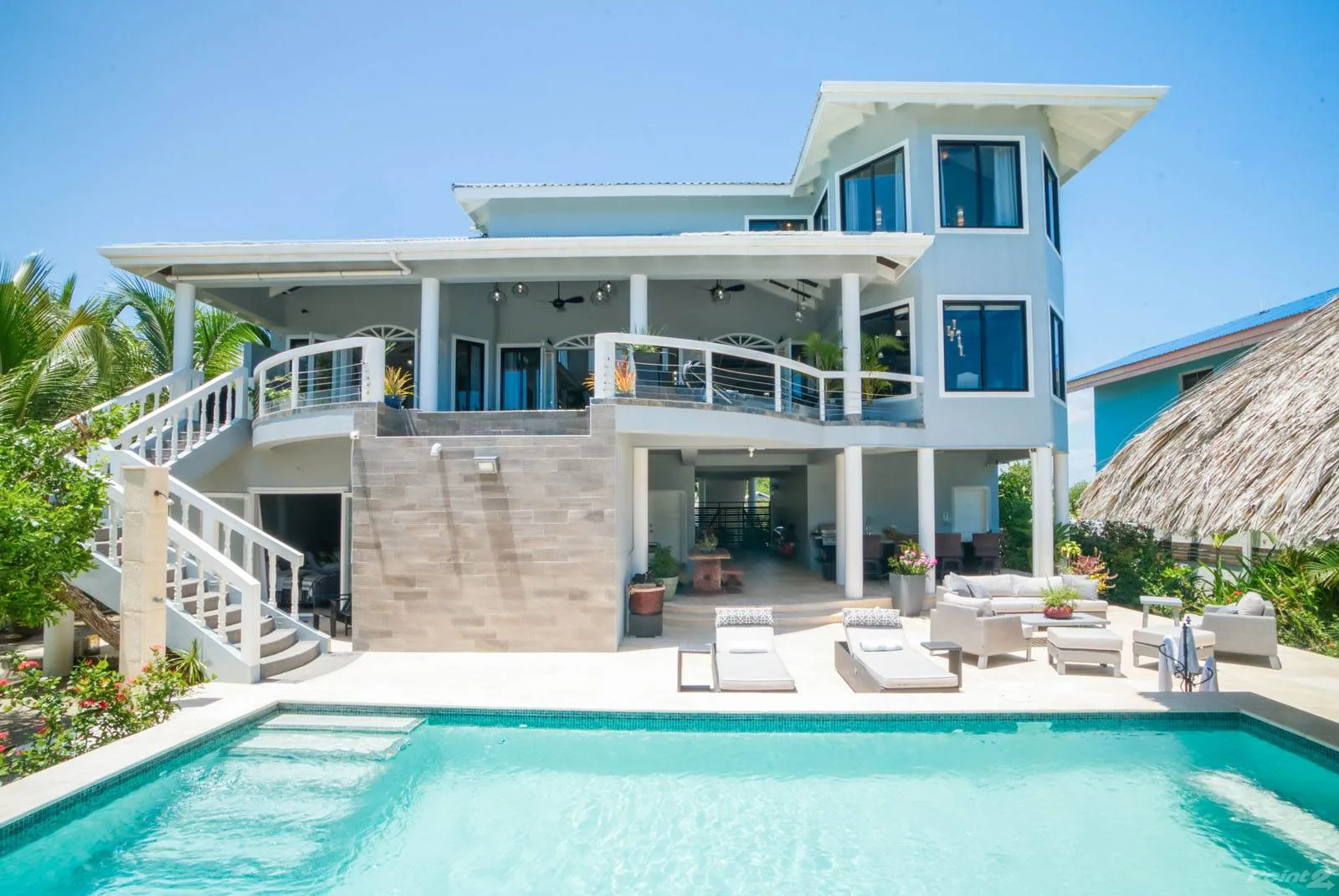 A modern house overlooks a swimming pool, with a terrace beside the water.