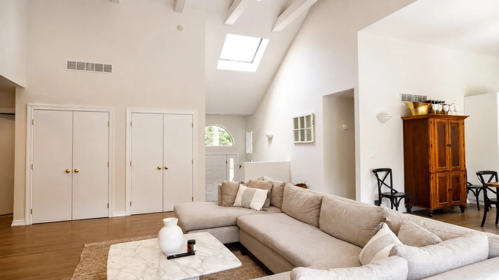 A bright living room with a large sectional seating area beneath a skylight.