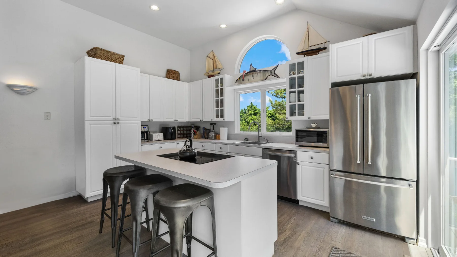 A bright kitchen with a large island and stainless steel refrigerator.