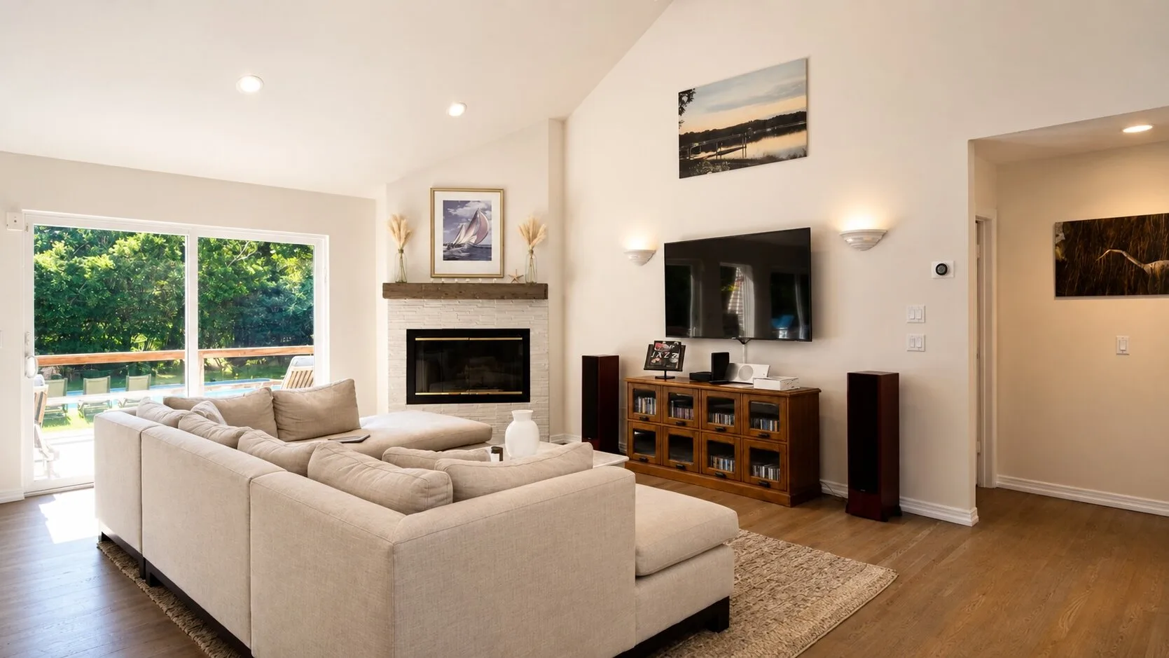 A bright living room with seating arranged around a fireplace and television.