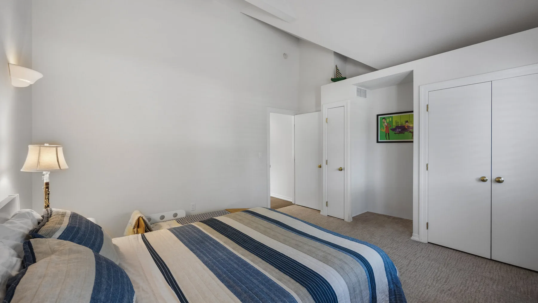 A bedroom with striped bedding and white closet doors.