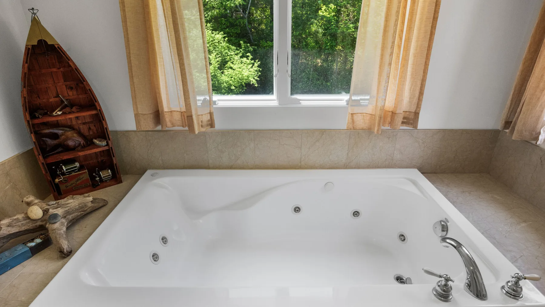 A bathroom features a large jetted bathtub beneath a window with beige curtains.