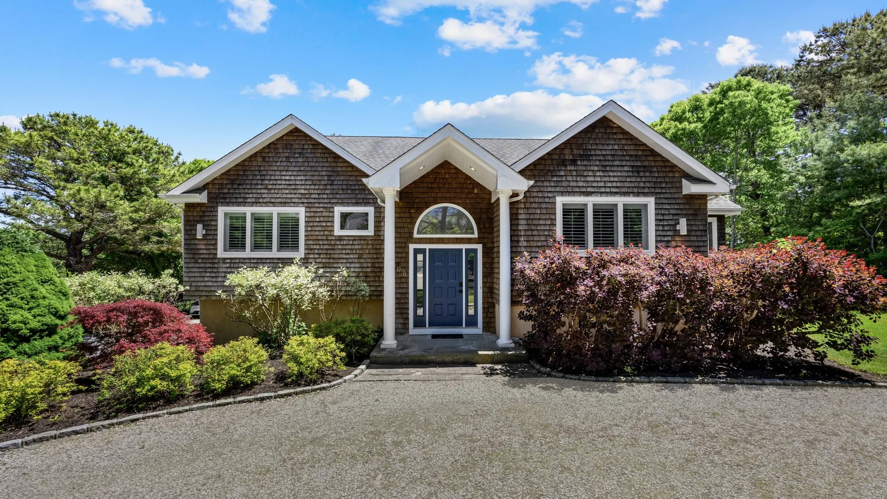 A detached house with a central entrance and landscaped shrubs.