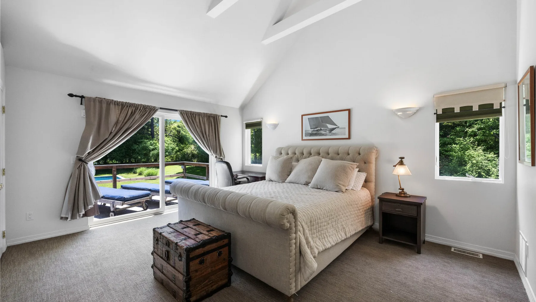 A bright bedroom with a large bed and windows overlooking greenery.