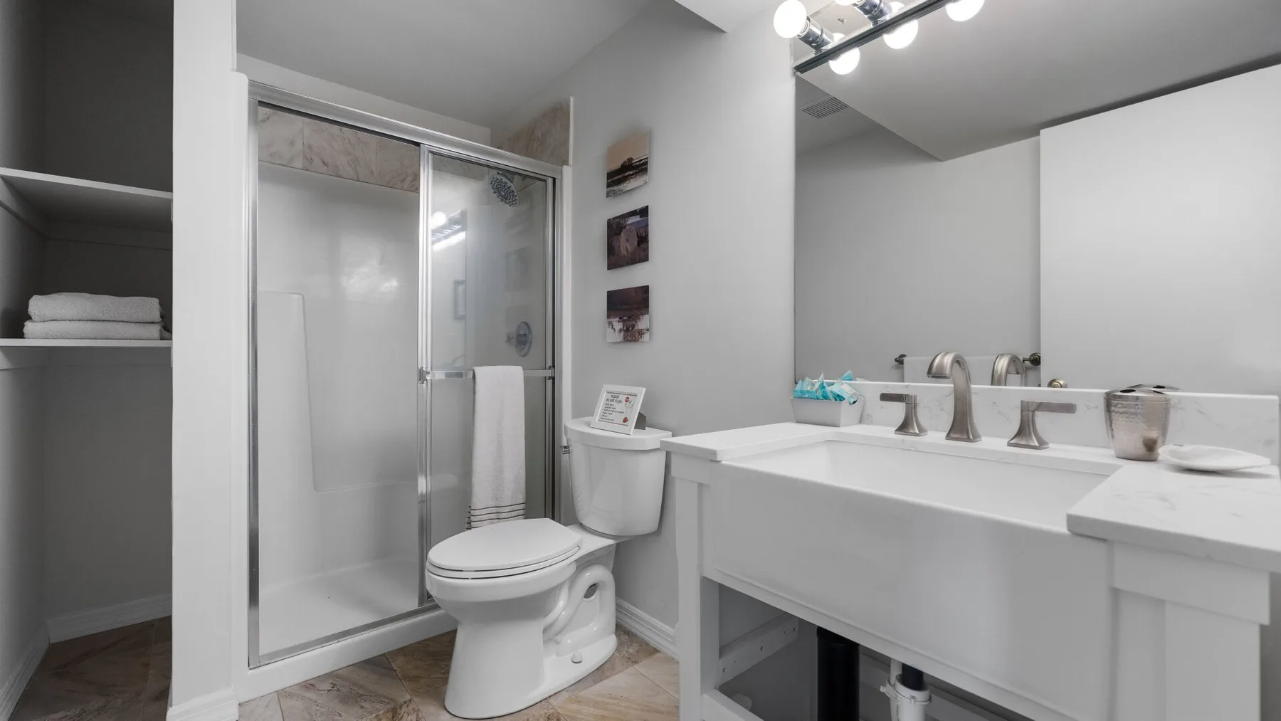 A bathroom with a glass shower, toilet, and long vanity.