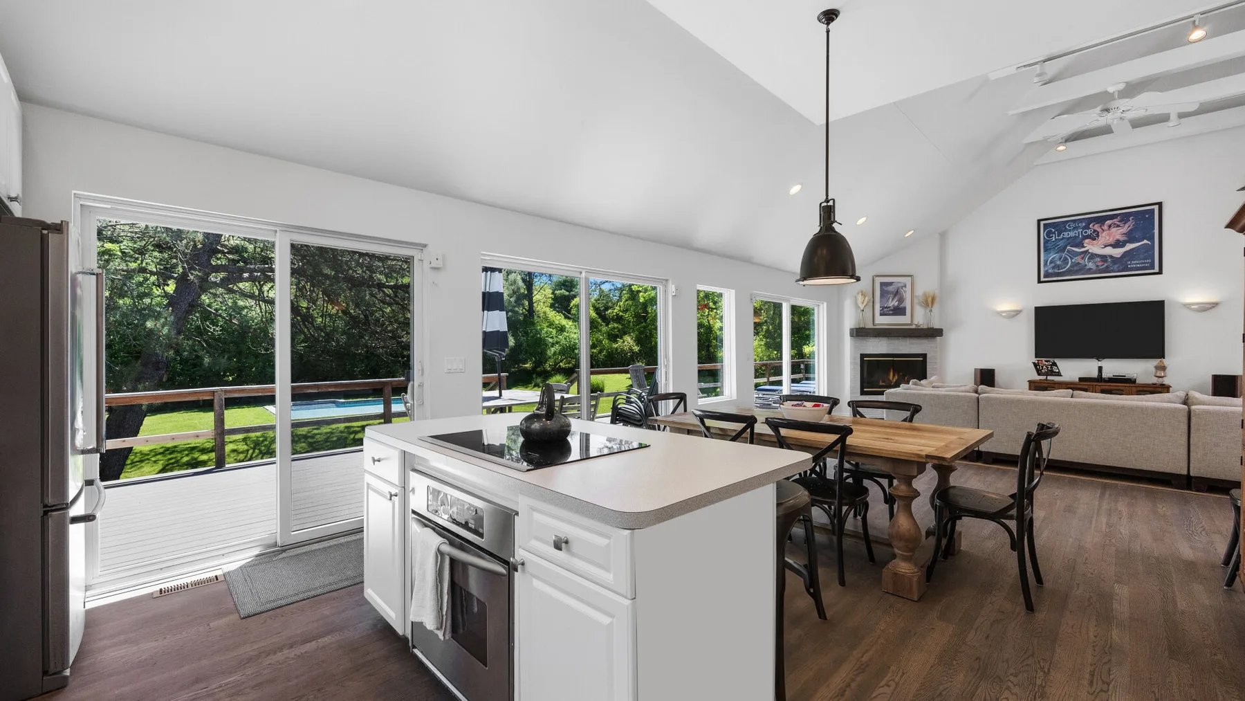 An open-plan kitchen and dining area with a large island and windows overlooking greenery.