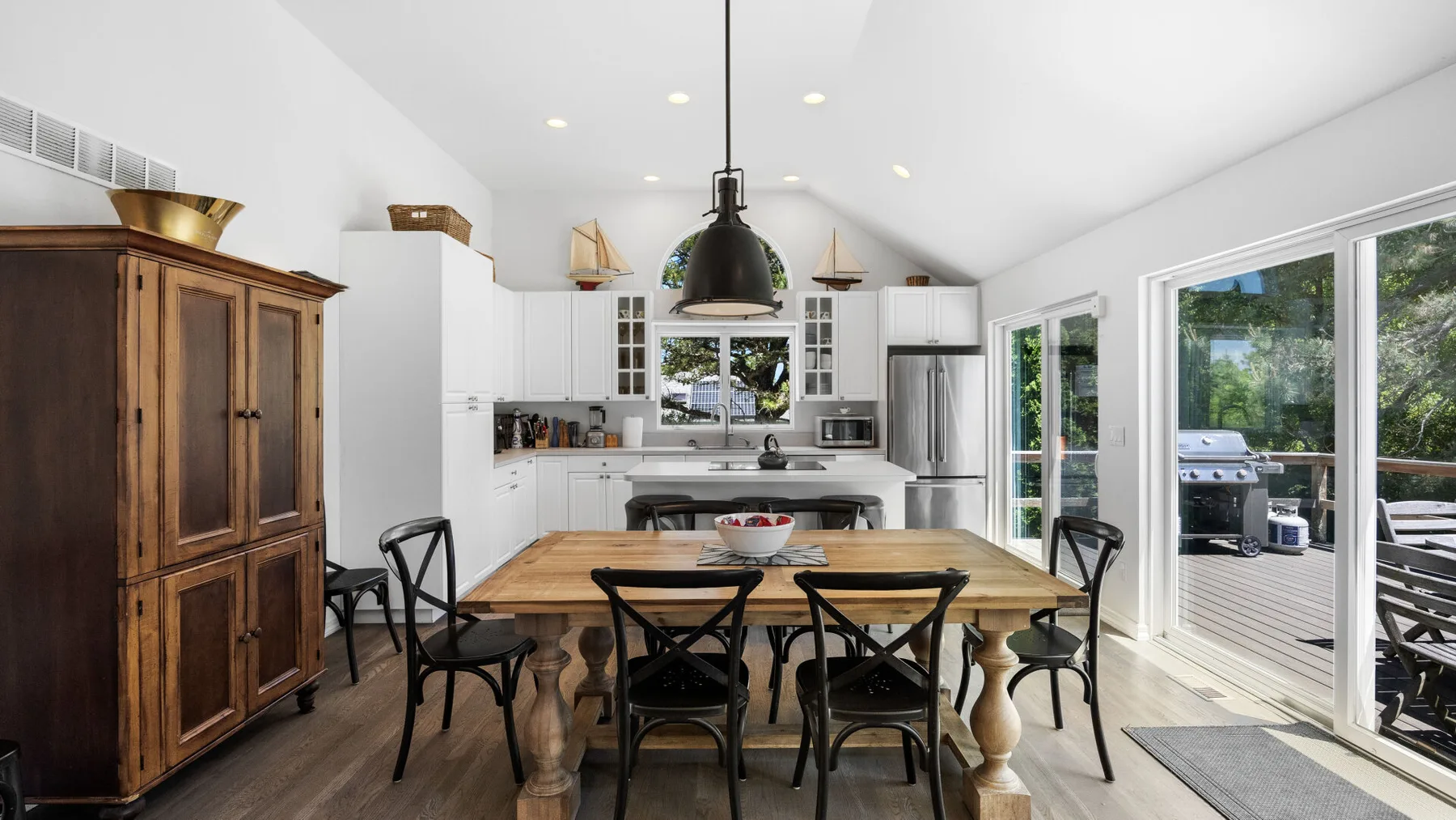A bright kitchen and dining area with a wooden table and large windows.