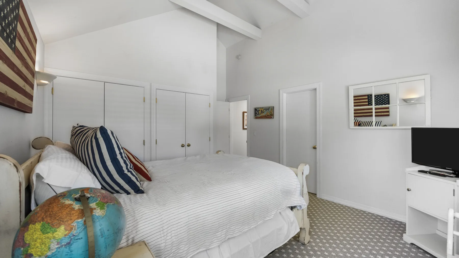 A bedroom with a neatly made bed and a globe beside it.