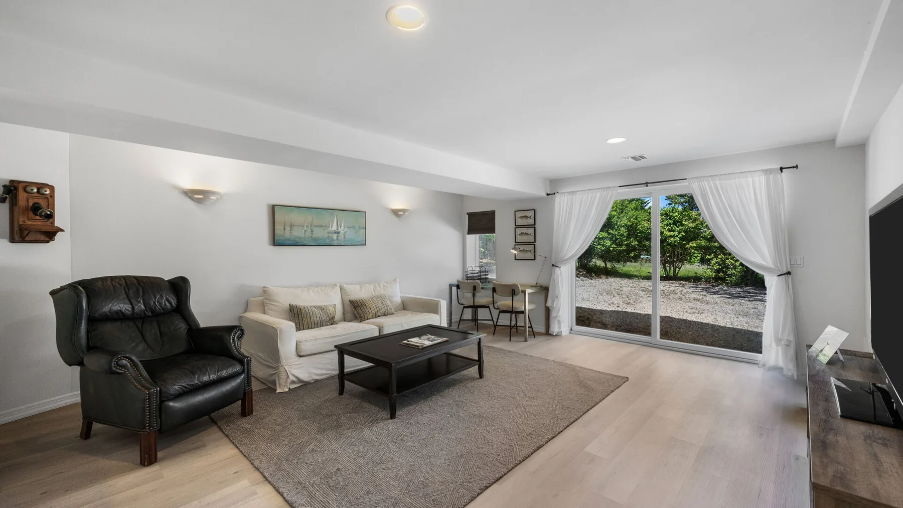 A bright living room with seating arranged around a coffee table and a large window.