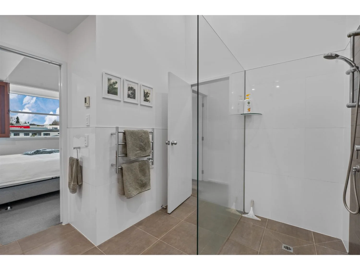 A bright bathroom with a shower and towels hanging on a rack.