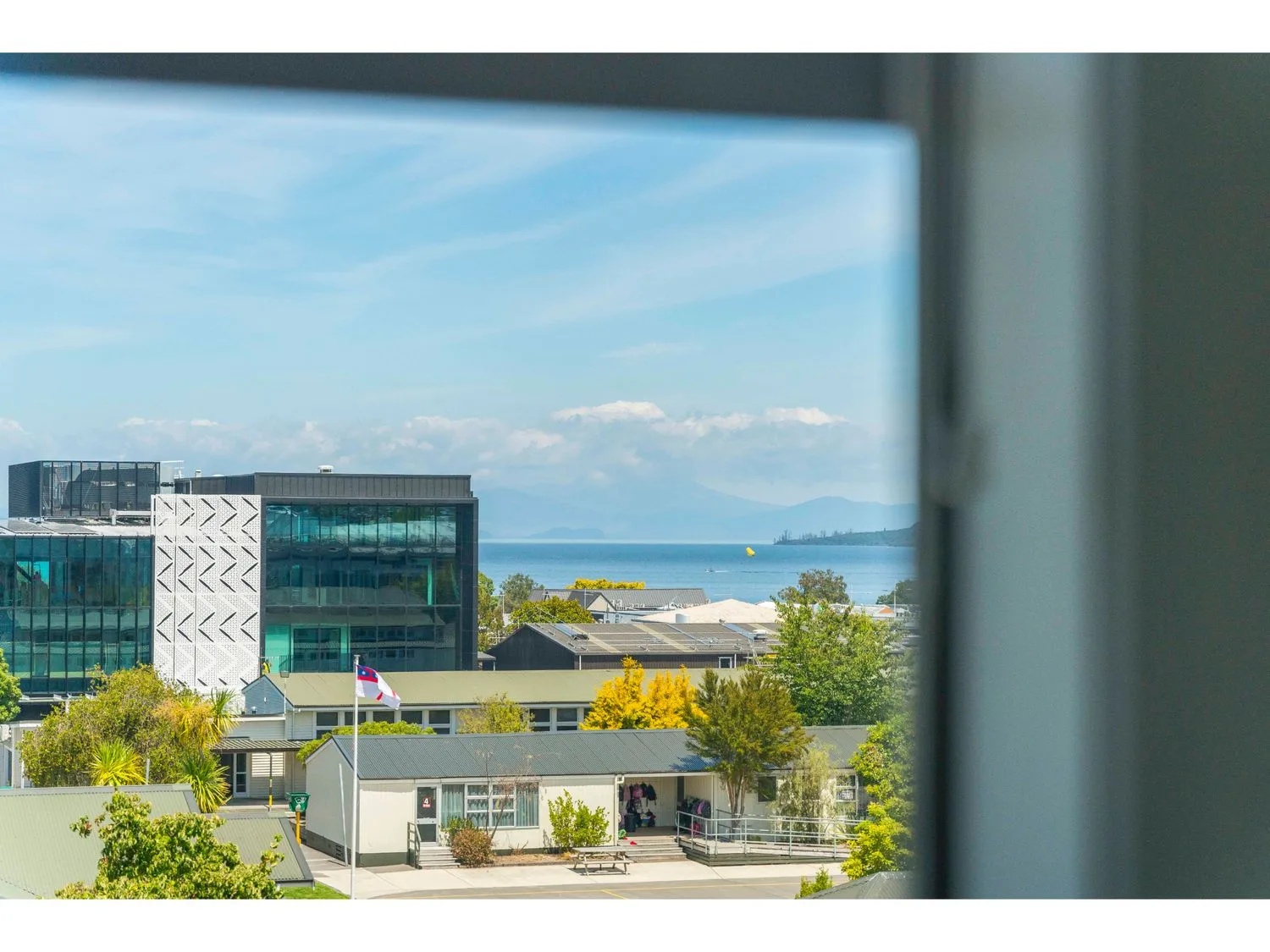 Buildings and trees are visible beside a lake through a window.