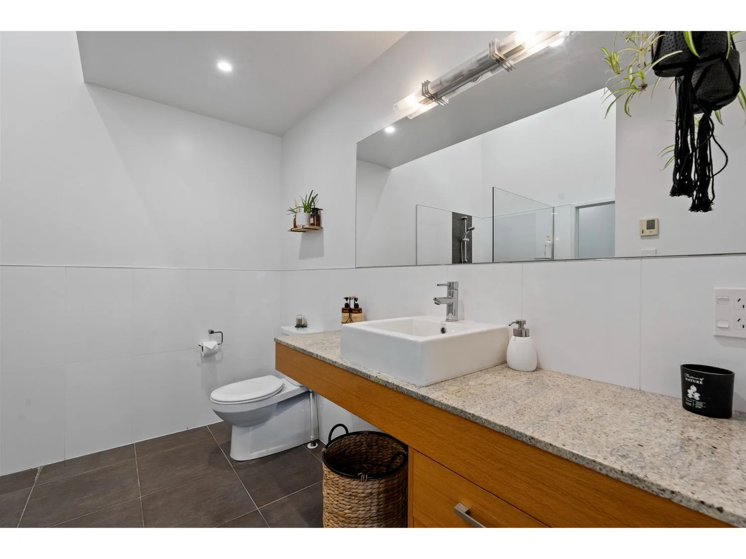 A bathroom with a toilet and a vessel sink on a long counter.