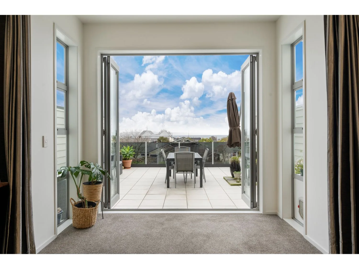 A living area opens onto a tiled outdoor terrace with a table and seating.