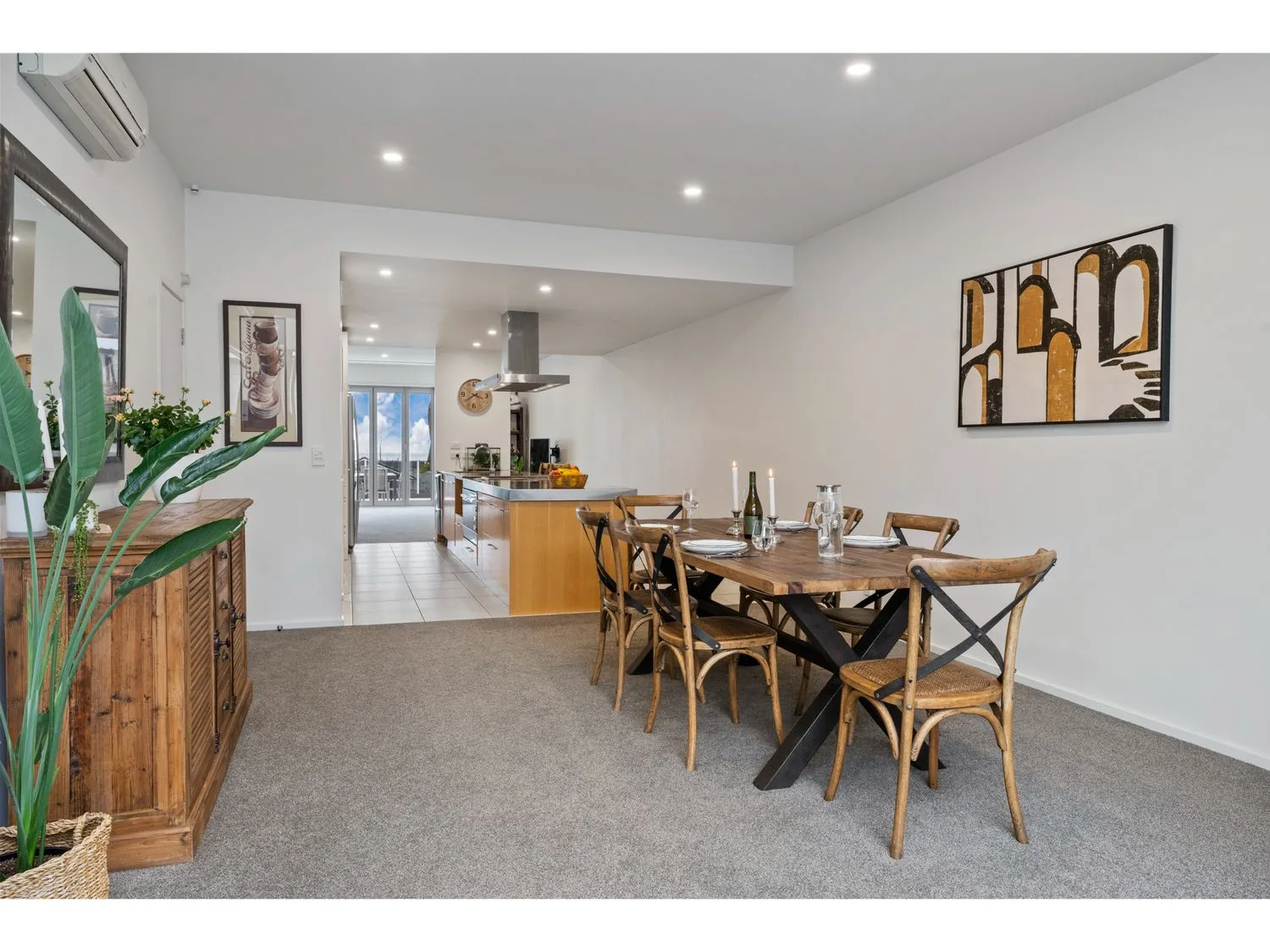Dining area with a wooden table and chairs beside an open kitchen.