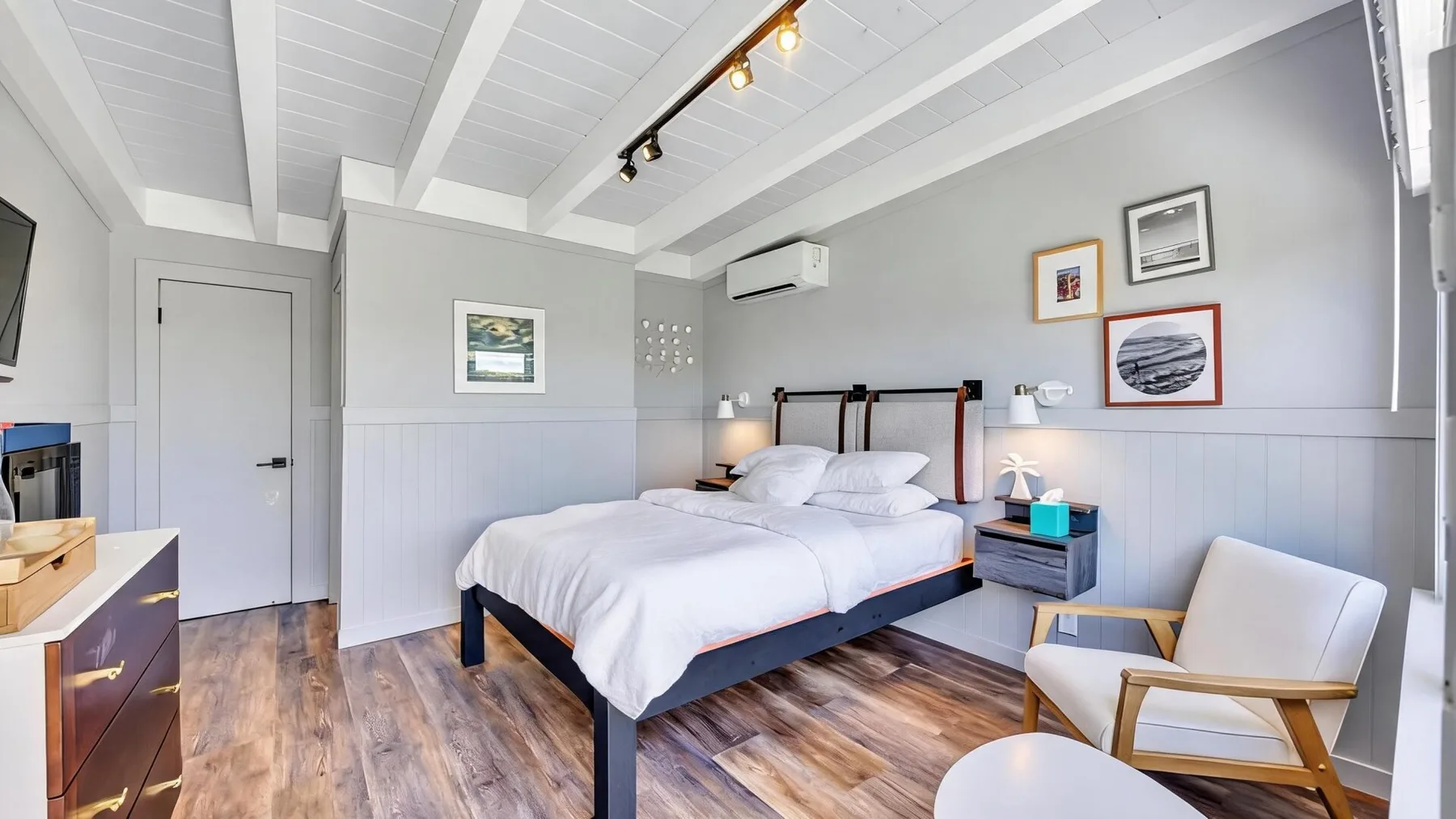 A bedroom with a neatly made bed and framed pictures on the wall.