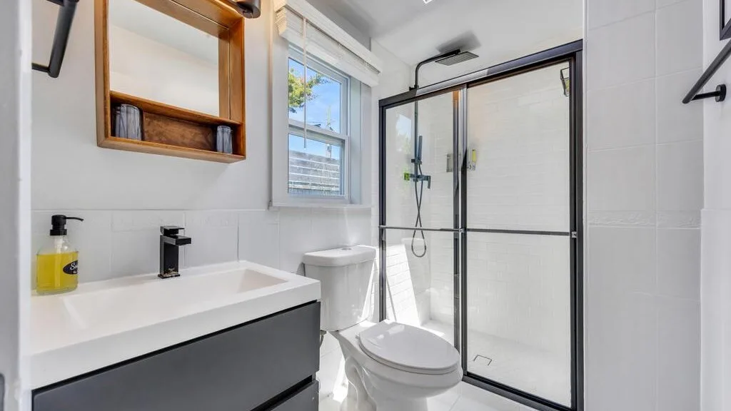 Un baño luminoso con lavabo, inodoro y ducha de vidrio.