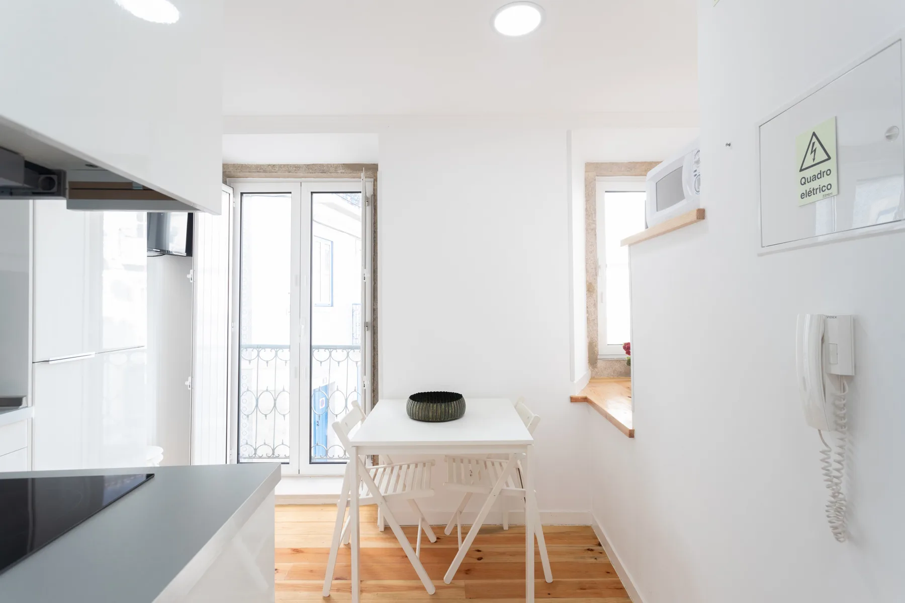 Una cocina luminosa con una pequeña mesa junto a las puertas del balcón.
