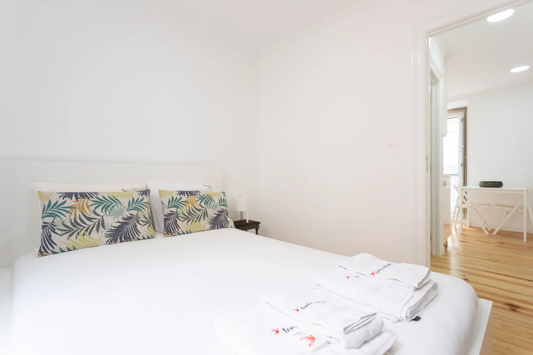 Un dormitorio luminoso con una cama y almohadas estampadas.