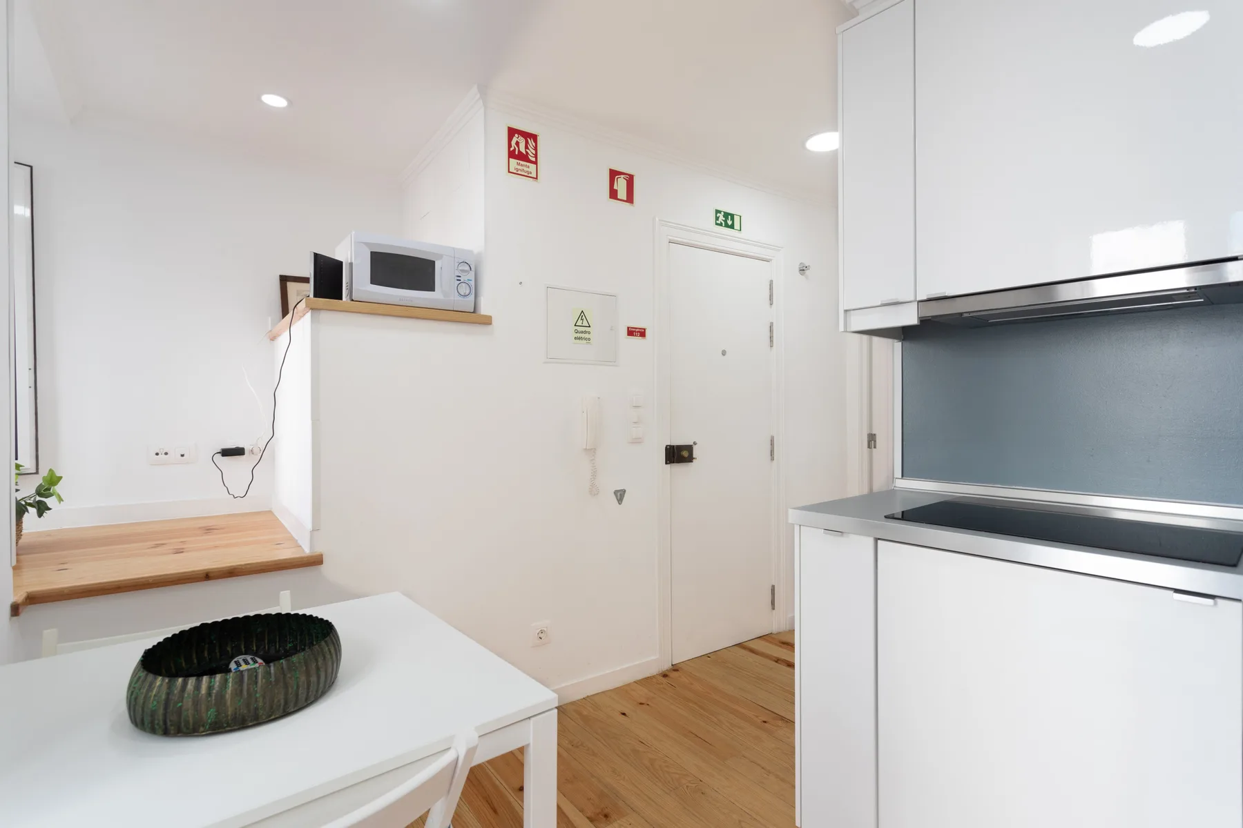 Una cocina compacta con armarios blancos, una encimera y una pequeña mesa.
