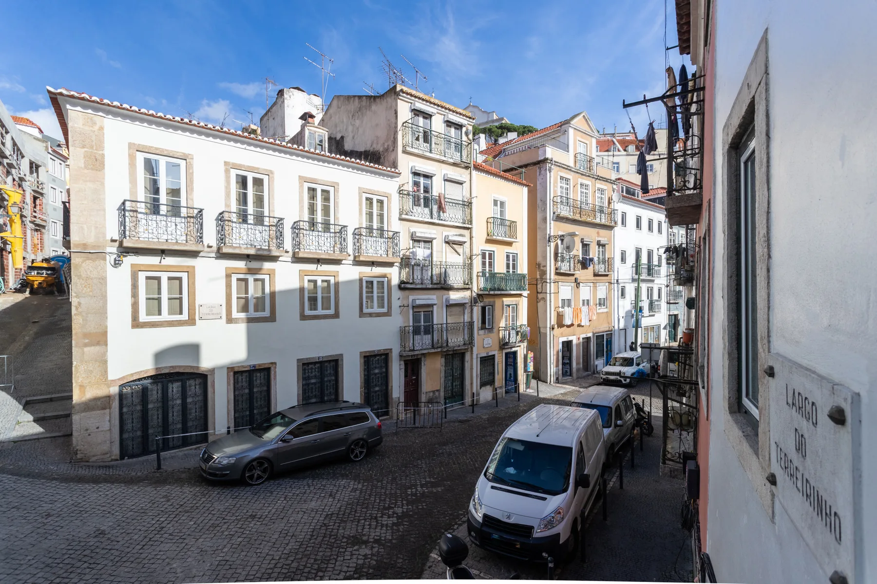 Una calle empedrada flanqueada por edificios de varias plantas y coches estacionados.